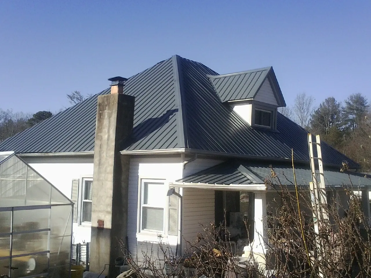 Dark blue standing seam metal roof on a white farmhouse with dormer — Slate & Tile Roof Repair by Roofing Brothers in Snohomish