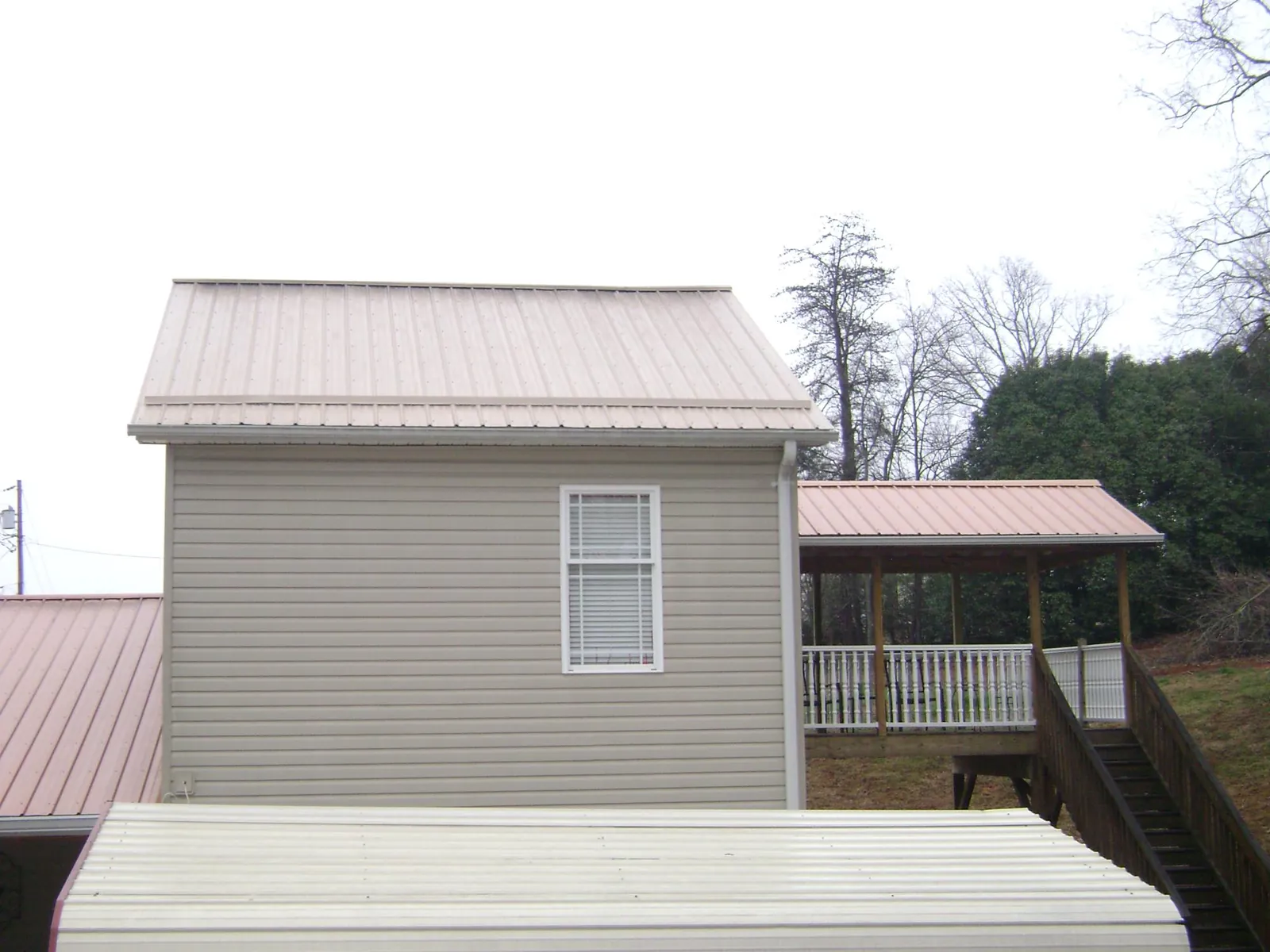 Tan metal roofs on a two story addition and attached porch, from a Roof Replacement job in Snohomish