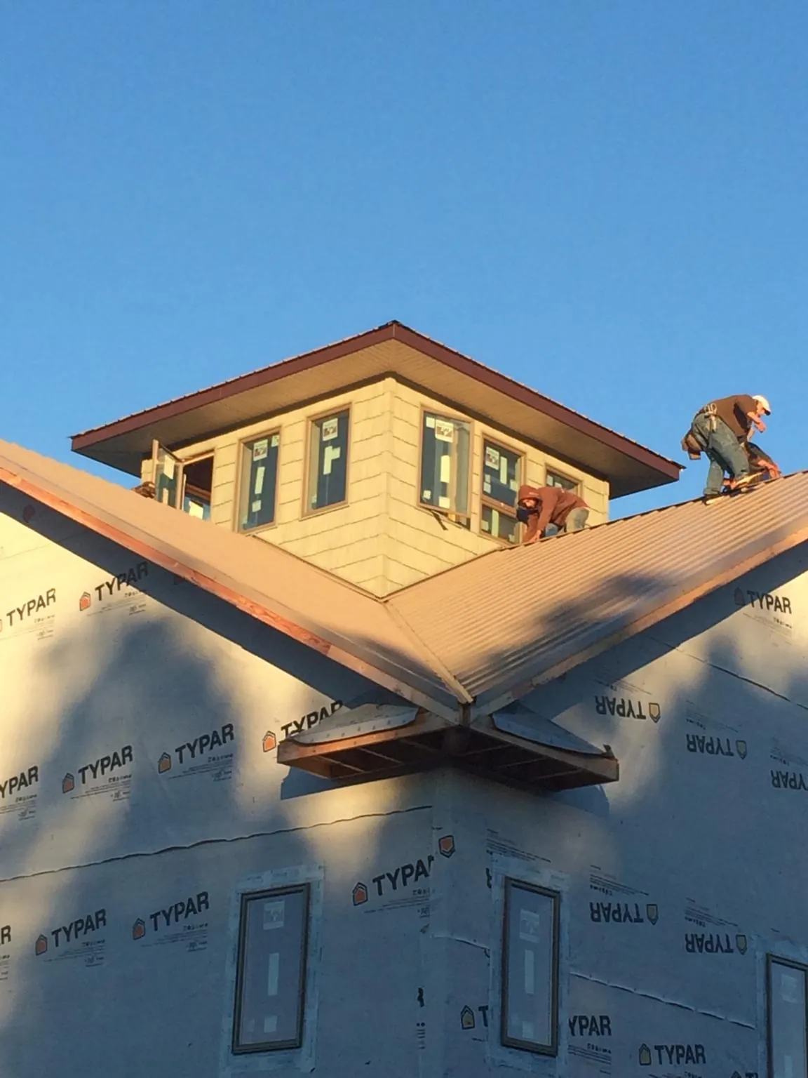 Roofers working around a rooftop cupola on a new metal roof at sunset — Roof Waterproofing in Snohomish by Roofing Brothers